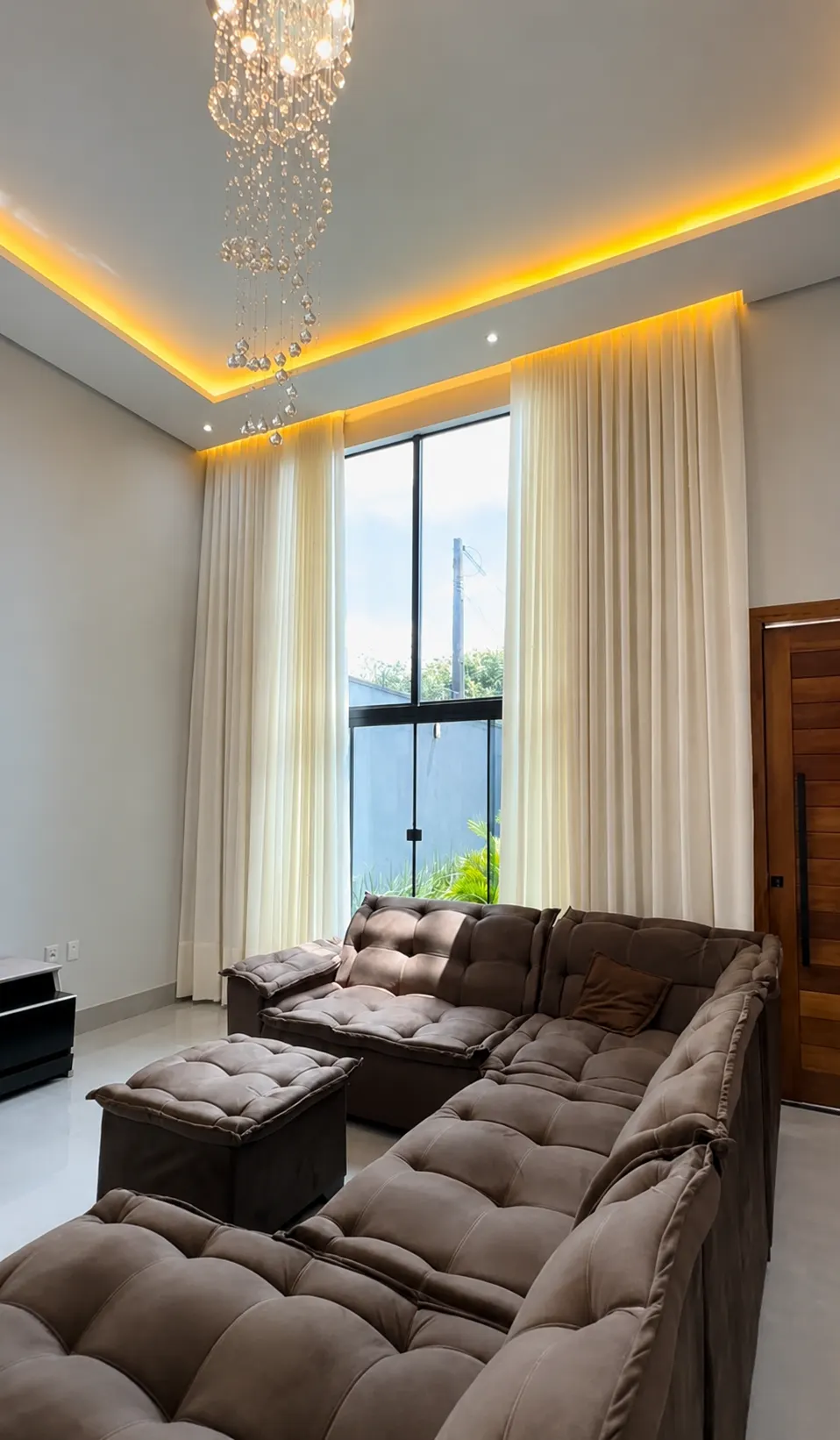 Sala de estar com pé-direito alto e cortina blackout em linho creme